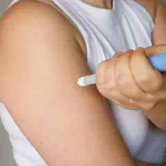 Osoba podaje sobie zastrzyk z lekiem, być może zawierającym fucibet lipid, w ramię.