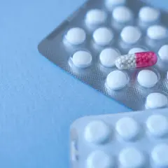 Dwie blistry białych tabletek, jedna z nich zawiera kapsułkę z różowymi granulkami, przypominającą clonazepam.
