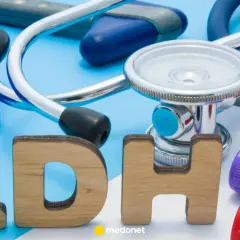 Drewniane litery "LDH" obok stetoskopu, rękawiczek i probówek z krwią.