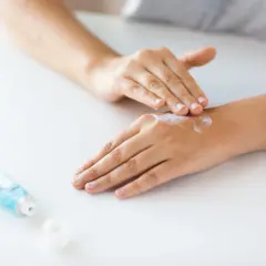 Dłonie rozsmarowują krem, by je nawilżyć i **cultivate** ich piękno. Obok leży tubka z kosmetykiem.