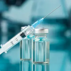 Strzykawka z igłą opiera się o fiolki. Może to być nalokson, lek ratujący życie w przypadku przedawkowania opioidów.