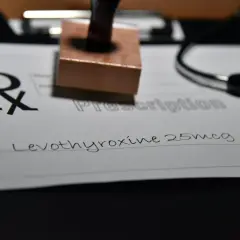 Recept na leki, na którym widnieje "Levothyroxine 25mcg". Obok stetoskop i pieczątka.