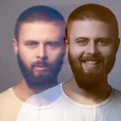 Dwóch mężczyzn z brodami, jeden uśmiechnięty, drugi z poważnym wyrazem twarzy, na szarym tle.