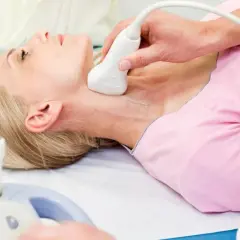 Badanie USG szyi kobiety przez lekarza.
