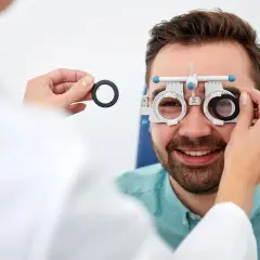 Mężczyzna w okularach próbnych podczas badania wzroku u optometrysty.