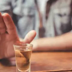 Dłoń odpycha kieliszek z alkoholem. Decyzja o abstynencji, jak naltex, jest ważna.