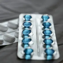 Dwa blistry leków: jeden z białymi kapsułkami, drugi z niebieskimi, prawdopodobnie pregabalin zentiva.