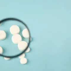 Pod lupą białe tabletki, jakby badano skład perazinu.