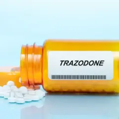 Pomarańczowa butelka leku Trazodone z rozsypanymi tabletkami.