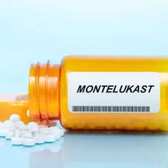 Pomarańczowa buteleczka z lekami na astmę, z napisem MONTELUKAST i rozsypanymi tabletkami.