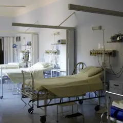 Puste łóżka szpitalne z aparaturą medyczną w sali intensywnej terapii.