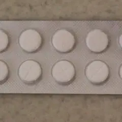 Opakowanie z dziesięcioma białymi tabletkami, niektóre z nacięciem. Może to być lek na receptę, np. tizagelan.