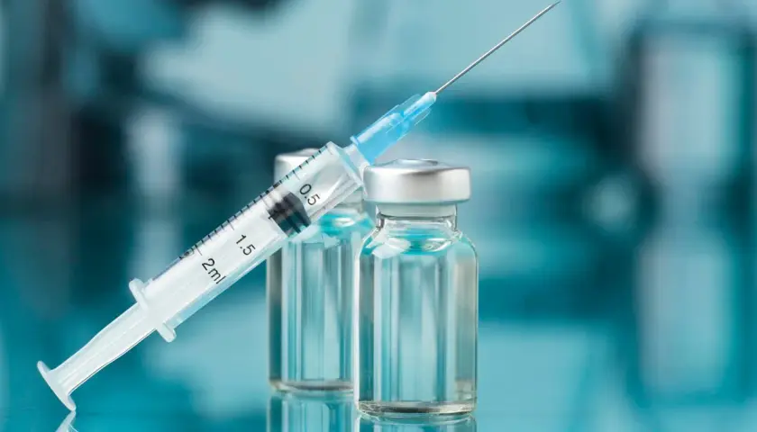 Strzykawka z igłą opiera się o fiolki. Może to być nalokson, lek ratujący życie w przypadku przedawkowania opioidów.