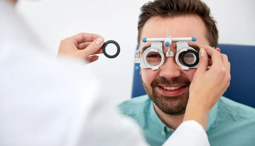 Mężczyzna w okularach próbnych podczas badania wzroku u optometrysty.