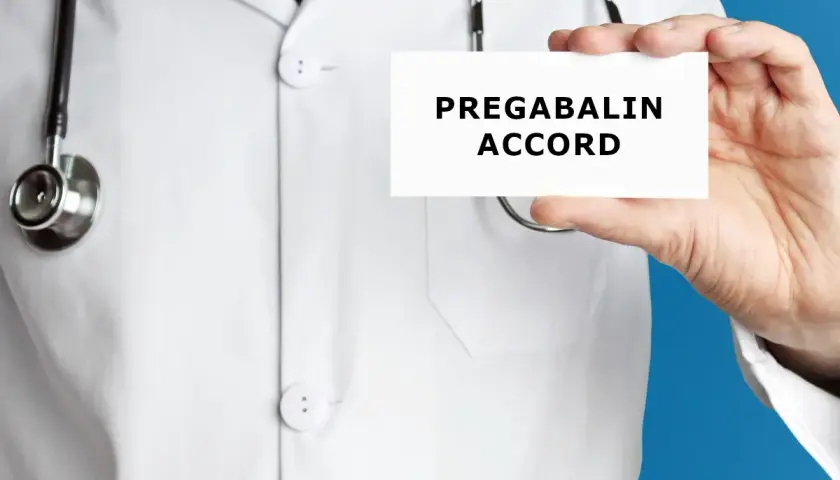 Lekarz w białym kitlu trzyma kartkę z napisem PREGABALIN ACCORD. Stetoskop wisi na jego szyi.