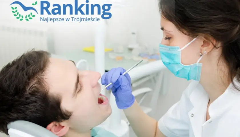 Dentystka w masce bada zęby pacjenta narzędziem stomatologicznym.