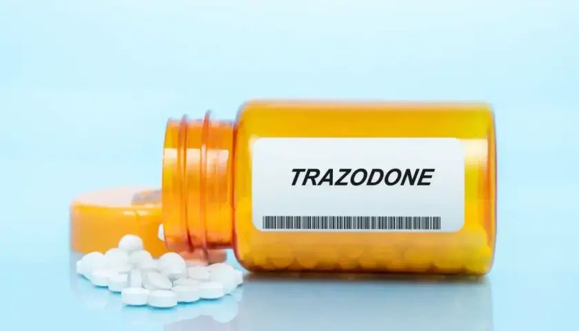 Pomarańczowa butelka leku Trazodone z rozsypanymi tabletkami.