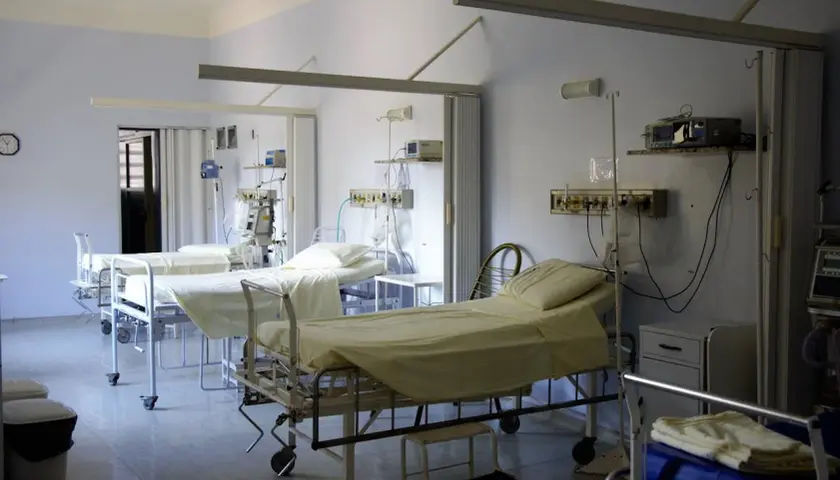 Puste łóżka szpitalne z aparaturą medyczną w sali intensywnej terapii.