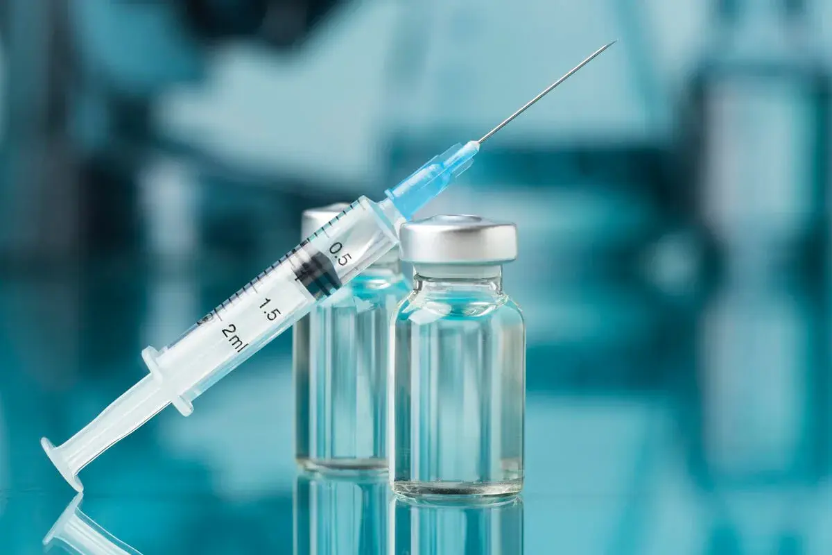 Strzykawka z igłą opiera się o fiolki. Może to być nalokson, lek ratujący życie w przypadku przedawkowania opioidów.