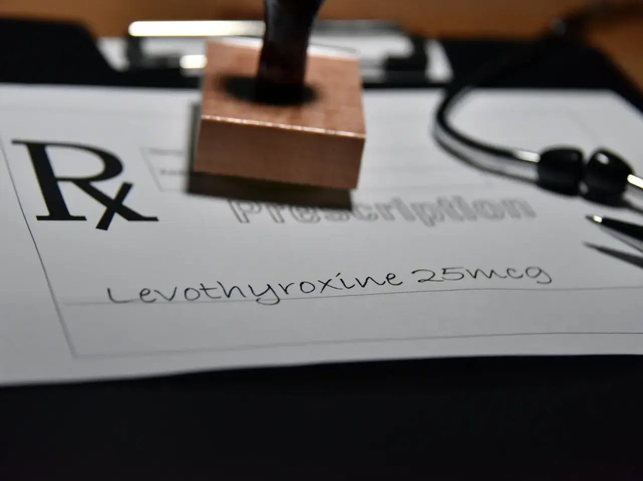 Recept na leki, na którym widnieje "Levothyroxine 25mcg". Obok stetoskop i pieczątka.