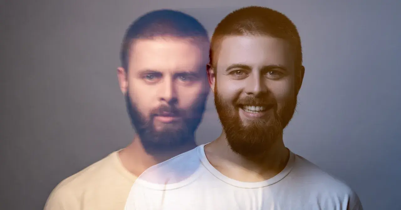 Dwóch mężczyzn z brodami, jeden uśmiechnięty, drugi z poważnym wyrazem twarzy, na szarym tle.