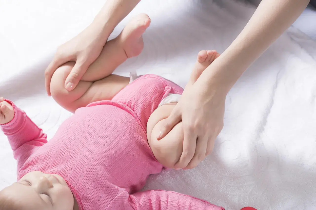 Delikatne ruchy dłoni rodzica pomagają w prawidłowym rozwoju stawów biodrowych dziecka, zapobiegając dysplazji.