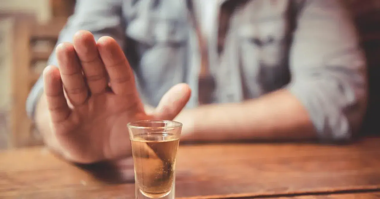 Dłoń odpycha kieliszek z alkoholem. Decyzja o abstynencji, jak naltex, jest ważna.