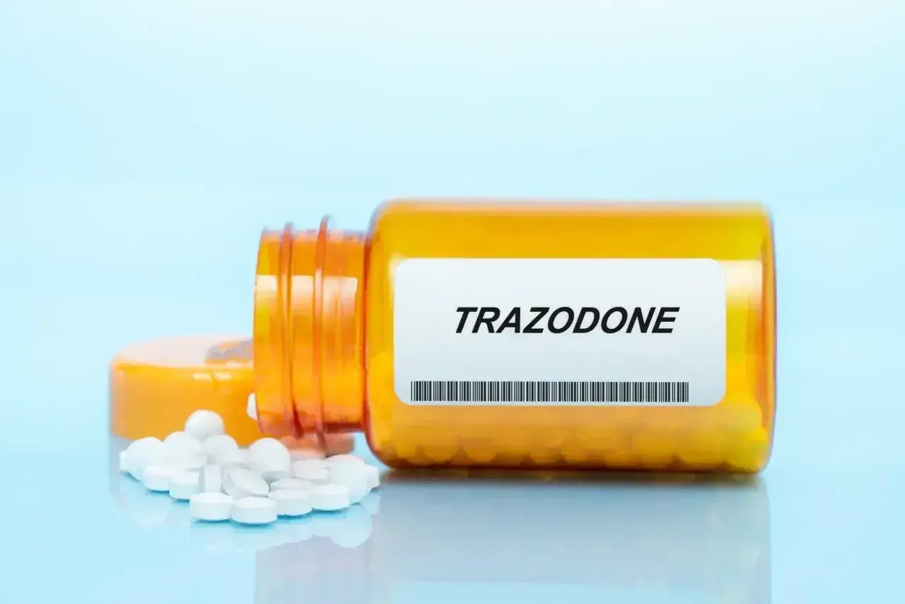 Pomarańczowa butelka leku Trazodone z rozsypanymi tabletkami.