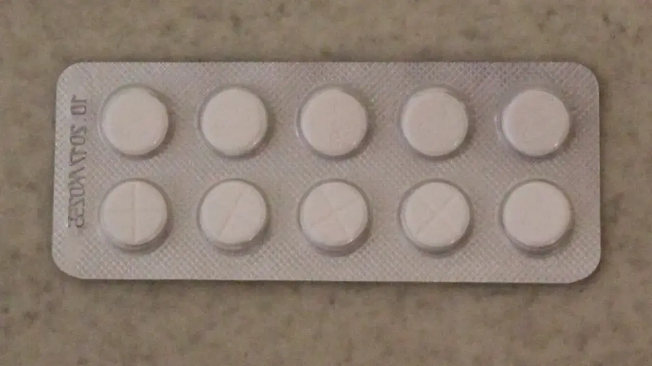 Opakowanie z dziesięcioma białymi tabletkami, niektóre z nacięciem. Może to być lek na receptę, np. tizagelan.